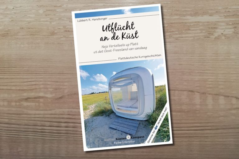 Umschlag des Buches "Utflücht an de Küst", erschienen 2025 bei BoD. Buchumschlag mit einem modernen, weißen, kubischen Strandkorb auf einem Weg in einer grünen Landschaft unter blauem Himmel.