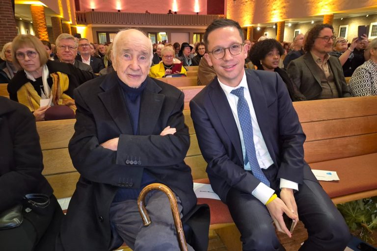 Weltstar Armin Mueller-Stahl und der niedersächsische Minister für Wissenschaft und Kultur, Falko Mohrs, am 15.11.2025 in der Martin-Luther-Kirche in Emden. 2 Männer in Anzug und Mantel sitzen in einer Kirchenbank, der eine hält einen Gehstock, im Hintergrund Publikum in einer beleuchten Kirche.